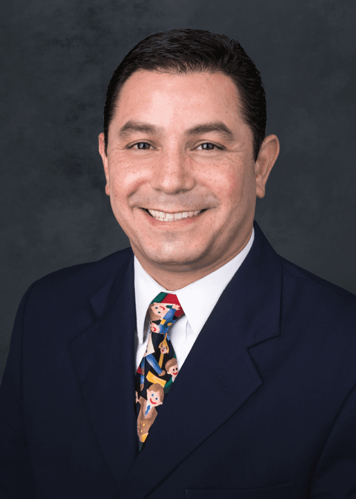 Headshot of Dr. Carlos Loredo Ritter, smiling and wearing a Safe the Children tie